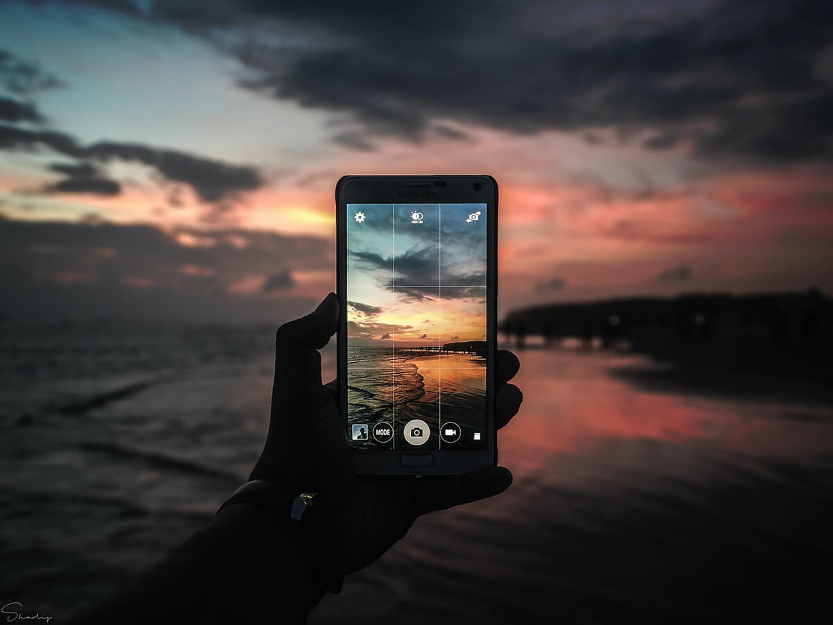 Person taking a sunset picture with their phone